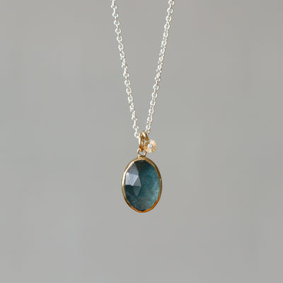 Rose Cut Moss Aquamarine Silver and Gold Theia Necklace #6 hanging in front of a wall, front angle