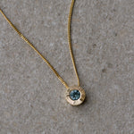 Light Green Montana Sapphire Medium Aurora Necklace in Yellow Gold on a neutral background, side angle