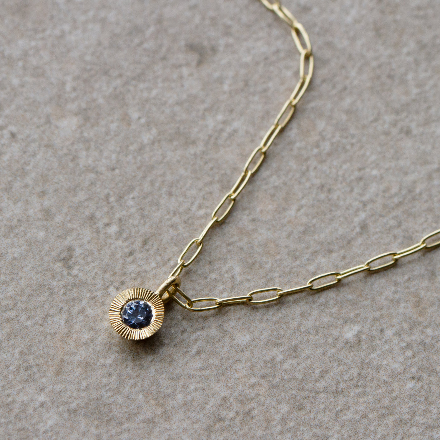Aurora Drop Pendant with Purplish Blue Montana Sapphire on Paperclip Chain in Yellow Gold on a neutral background, front side to the right