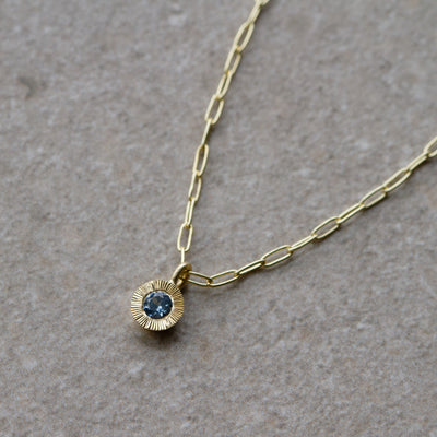 Aurora Drop Pendant with Purplish Blue Montana Sapphire on Paperclip Chain in Yellow Gold on a neutral background, right side