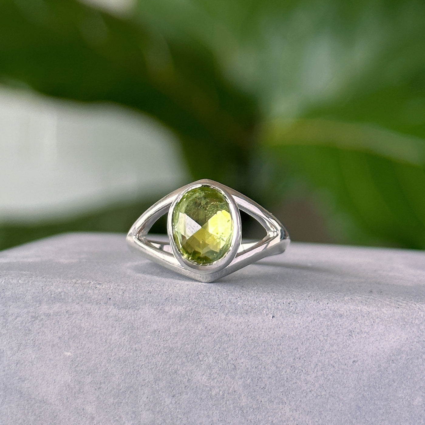 Peridot Cleo Ring in Sterling Silver sitting on a concrete table, front angle 