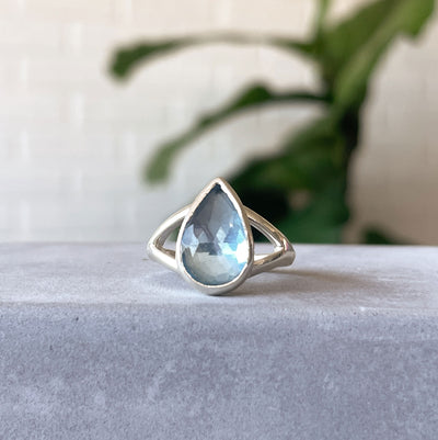 Swiss Blue Topaz Cleo Ring in Sterling Silver #1 on a concrete table, front angle