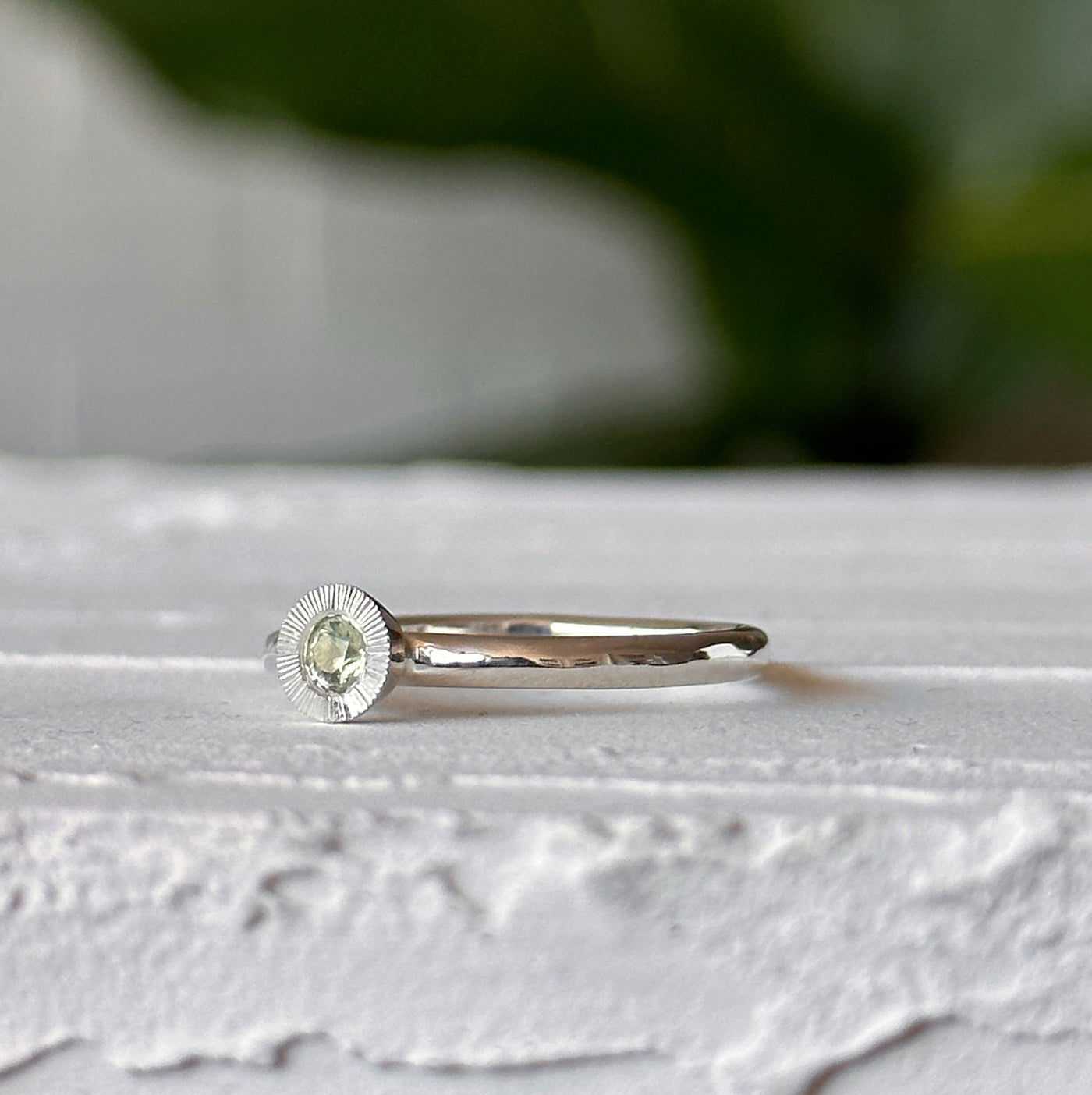Light Green Montana Sapphire Large Aurora Stacking Ring in Silver sitting on a white table, side angle