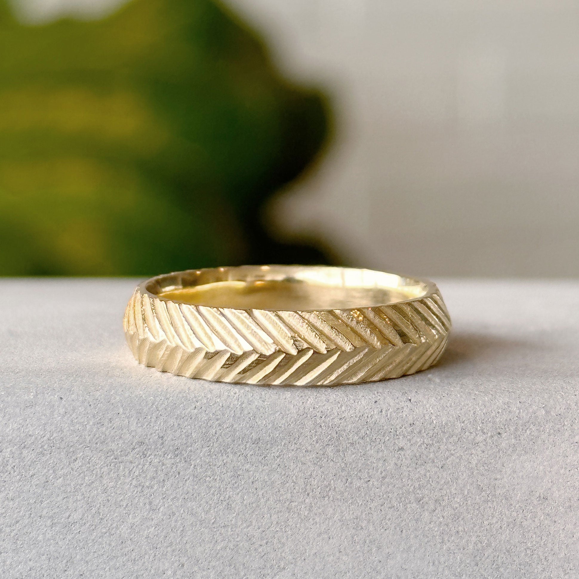 Herringbone Wide Band in gold on a gray background