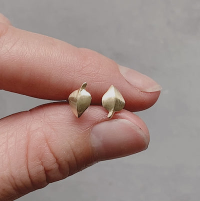 Yellow Gold Aspen Stud Earrings between two fingers by Corey Egan