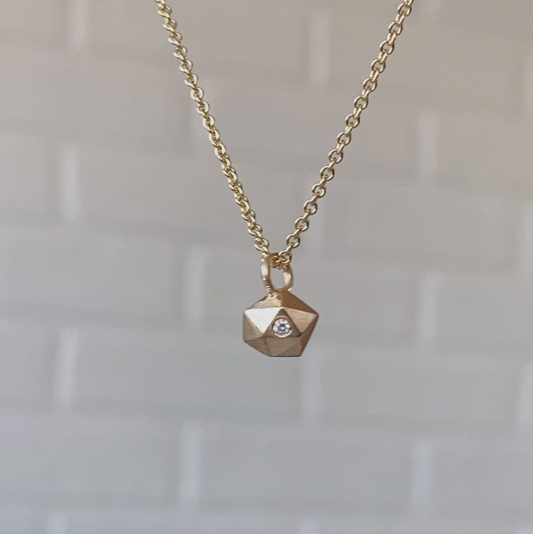 Faceted geometric gold tiny fragment necklace with a single white diamond in one facet on a white background | Corey Egan