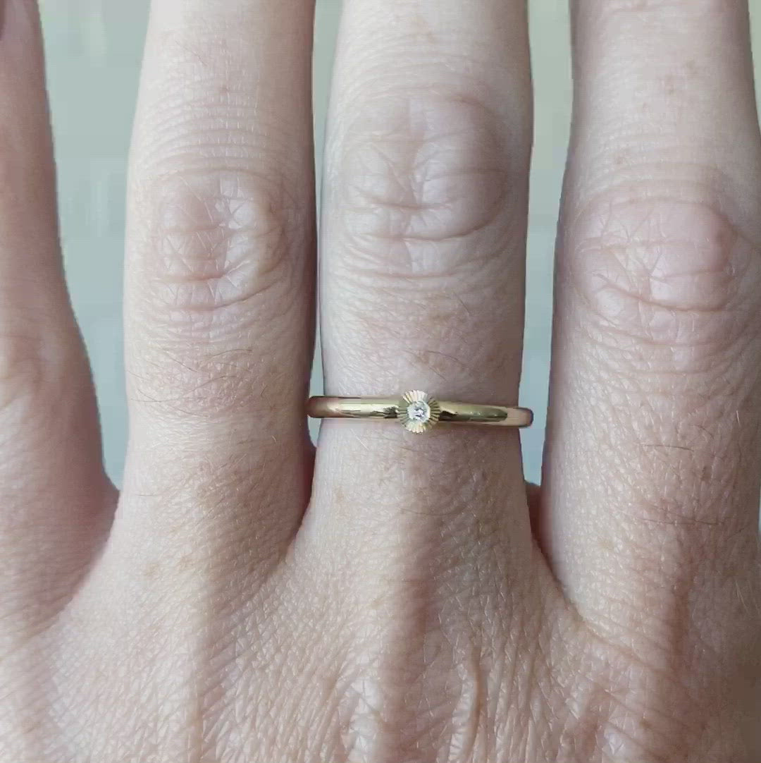 14k yellow gold small aurora stacking ring with a 1.5mm center diamond and engraved border on a hand