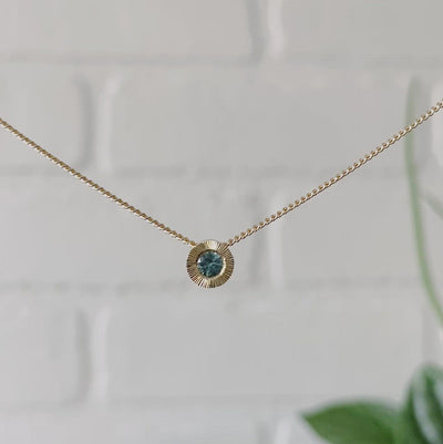 14k yellow gold small aurora necklace with a teal Montana sapphire center 