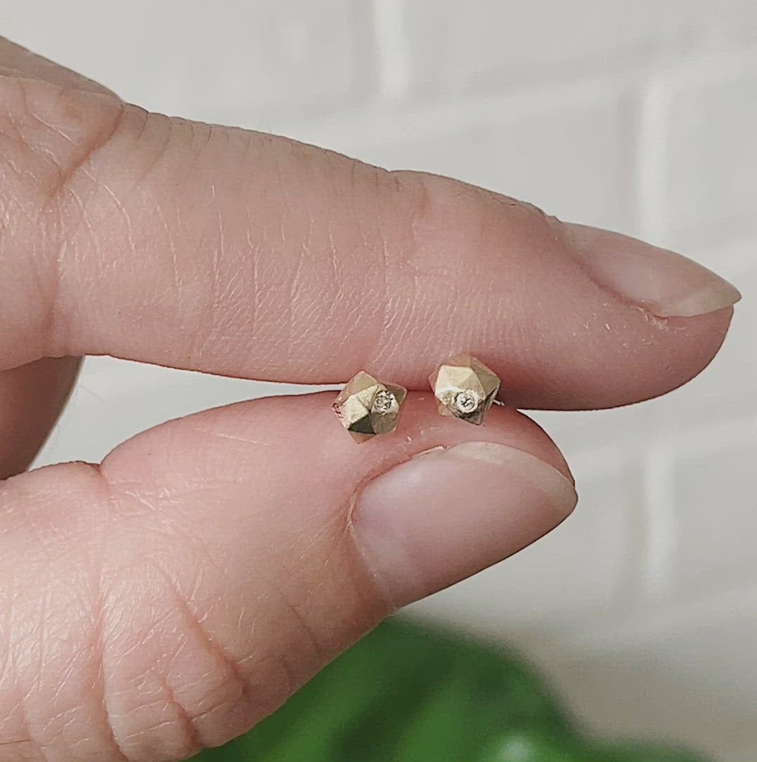 14k yellow gold geometric faceted stud earrings with diamonds in the micro size between two fingersby Corey Egan