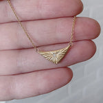 Triangular gold flash necklaw eith a diamond center and sunburst carved motif in 14k yellow gold in a hand by Corey Egan