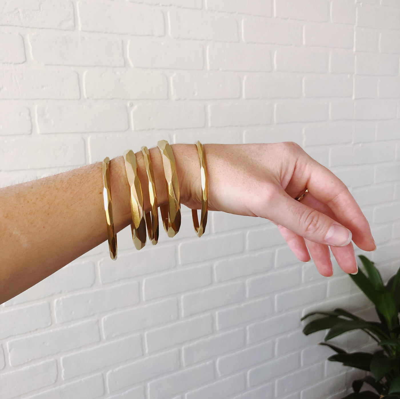 stackable faceted yellow bronze bangle bracelets in two sizes: Thin and Regular. Displayed on a woman's wrist