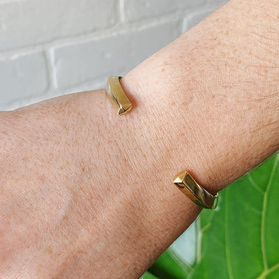 Bronze minimal cuff bracelet with faceted sides and pentagon shaped ends on a wrist