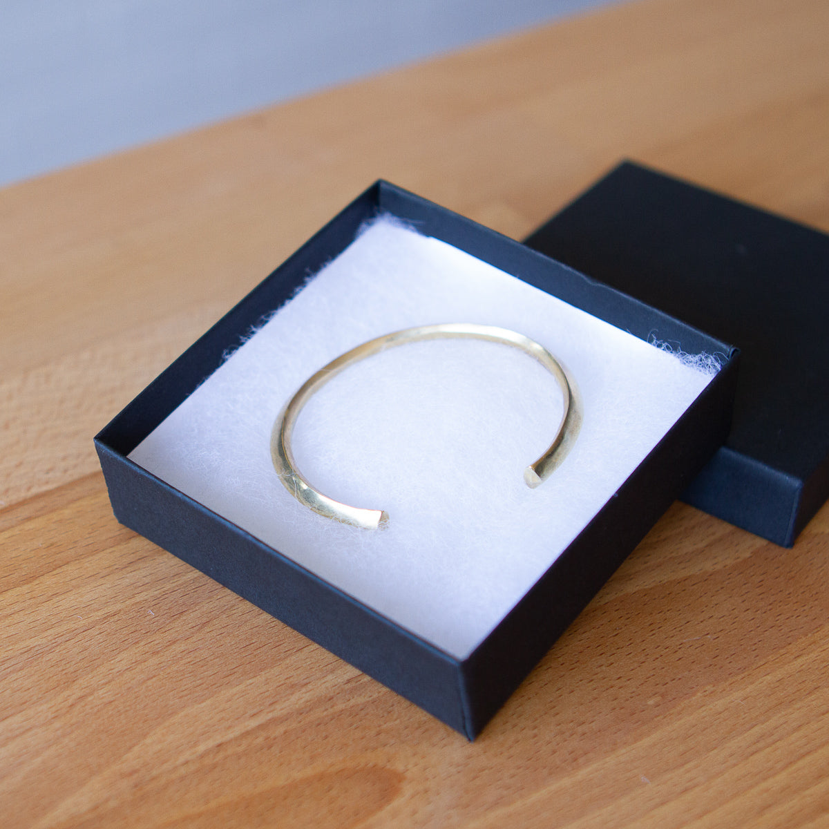 Bronze minimal cuff bracelet with faceted sides and pentagon shaped ends in a gift box