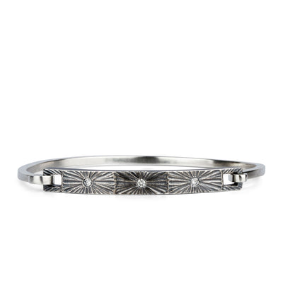 Oxidized sterling silver bar bracelet with three diamonds and a carved sunburst around each by Corey Egan on a white background