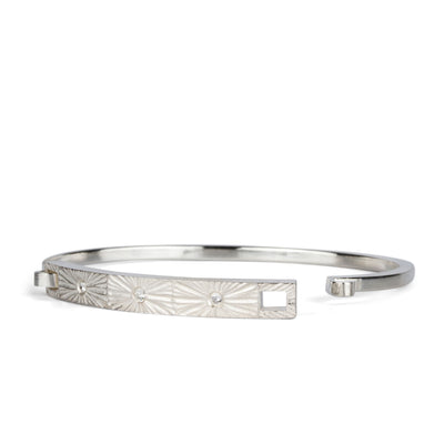 Sterling silver bar bracelet with three diamonds and a carved sunburst around each by Corey Egan on a white background side view