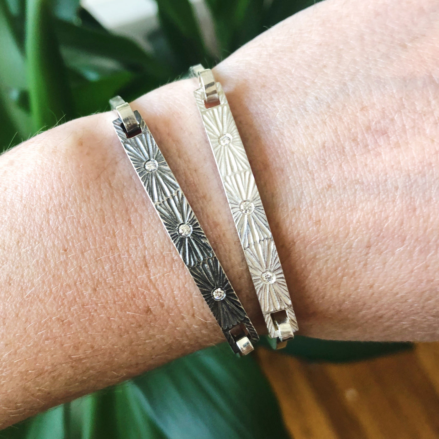 Sterling silver bar bracelet with three diamonds and a carved sunburst around each in bright and oxidized silver on a wrist by Corey Egan