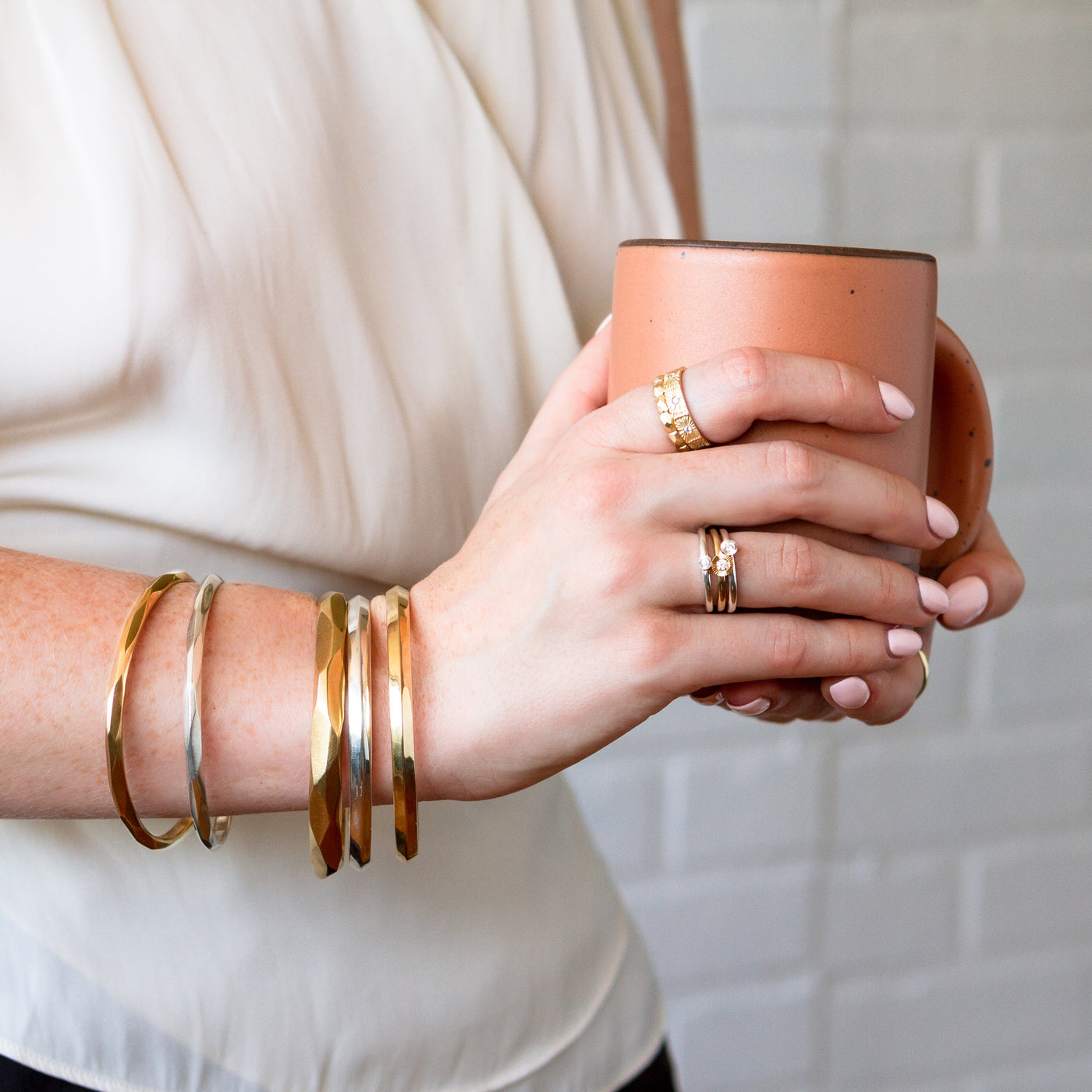 A model wears assorted silver and bronze bracelets including the silver thin denali bangle