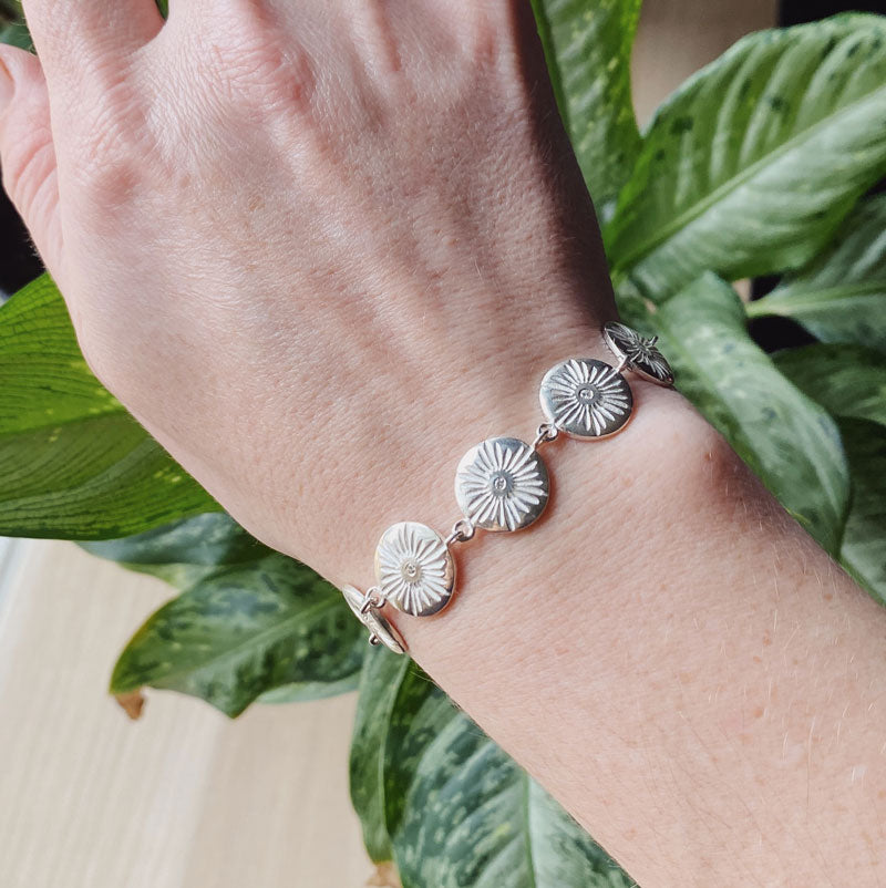 Sterling silver round sunburst link bracelet with diamond centers on a wrist by Corey Egan 