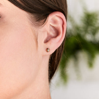Gold Ladybug Stud Earrings on an ear by Corey Egan