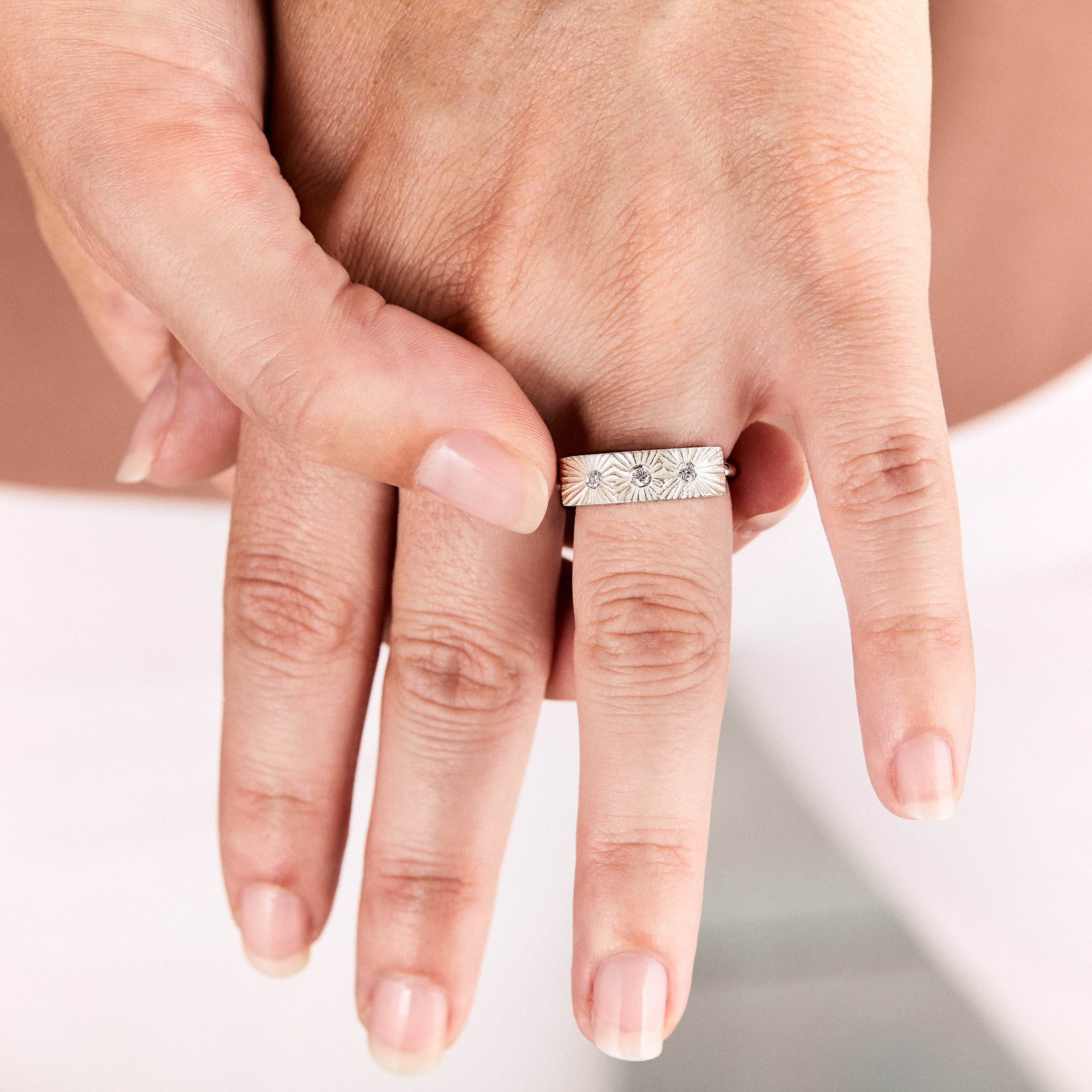 Sterling silver bar ring with three diamonds and a carved sunburst design around each by Corey Egan on a hand vie #2