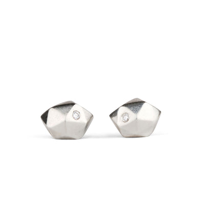 Sterling silver wabi-sabi faceted geometric stud earrings with two flush set diamonds by Corey Egan on a white background
