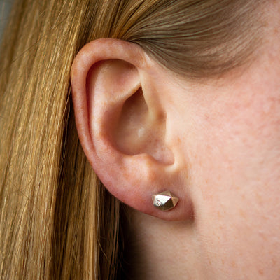 Sterling silver wabi-sabi faceted geometric stud earrings with a flush set diamond by Corey Egan on an ear