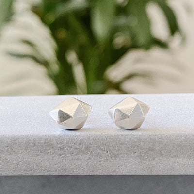 Sterling silver wabi-sabi faceted geometric stud earrings by Corey Egan on concrete front view