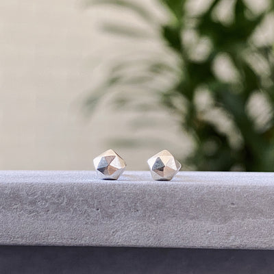 sterling silver micro size geometric faceted stud earrings by Corey Egan on concrete