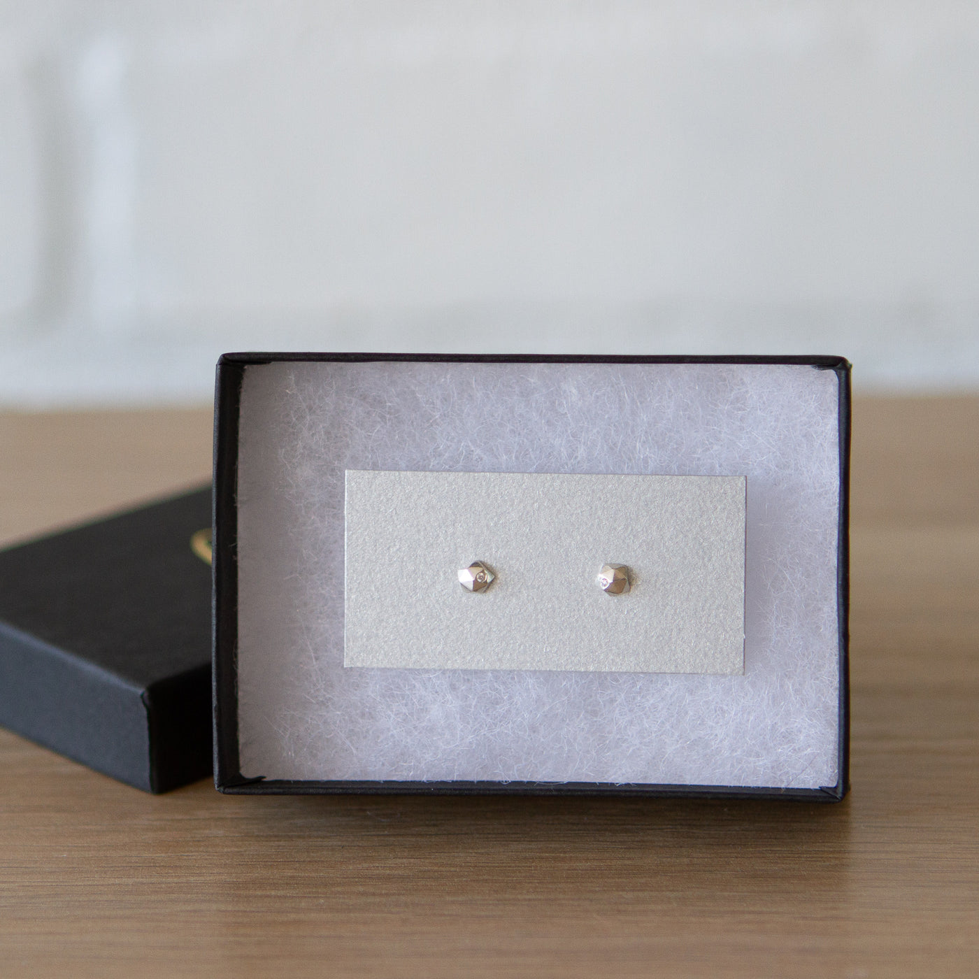 sterling silver micro size geometric faceted stud earrings with a single flush set diamond by Corey Egan in a gift box