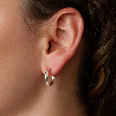 Sterling silver small faceted hoop earrings with posts on an ear by Corey Egan 