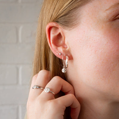 silver diamond droplet stud earrings with silver nimbus dangles and silver denali hoops on an ear