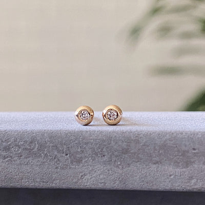 yellow gold and diamond droplet studs on concrete
