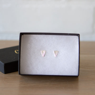 Sterling silver triangular stud earrings with a carved sunburst texture by Corey Egan in a gift box
