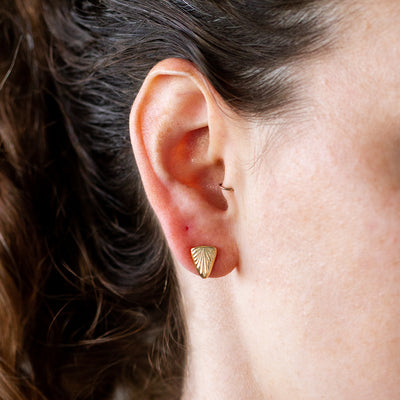 Triangle sunburst stud earrings in gold vermeil on an ear