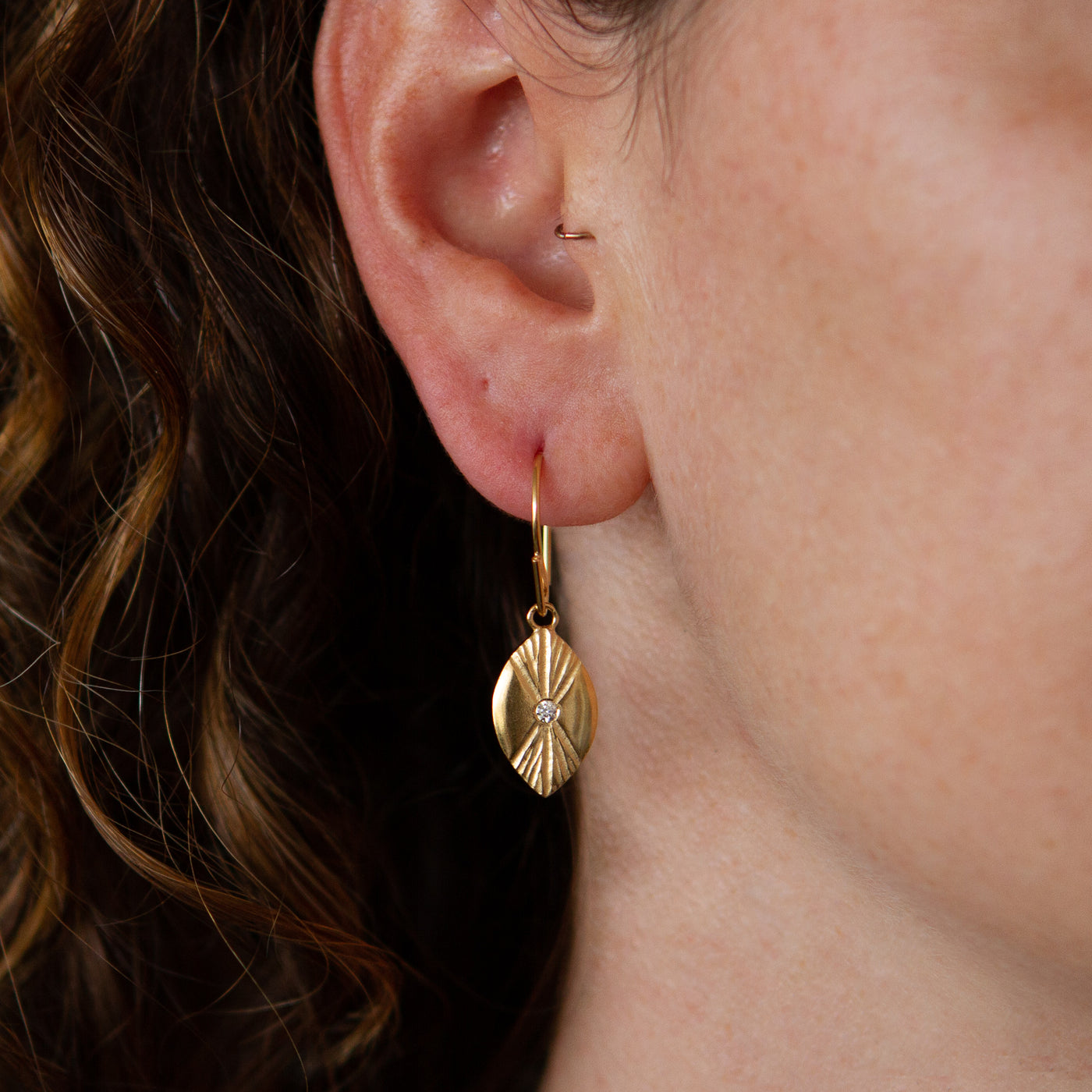 Vermeil Lumens Eye Dangle Earrings with diamond centers by Corey Egan on an ear