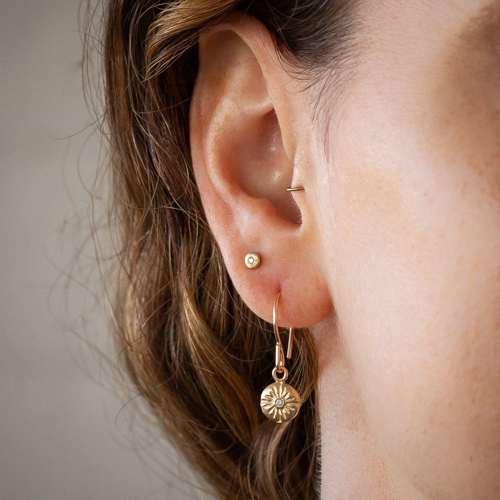 Gold and Diamond Small carved sunburst Lucia Dangle Earrings on an ear