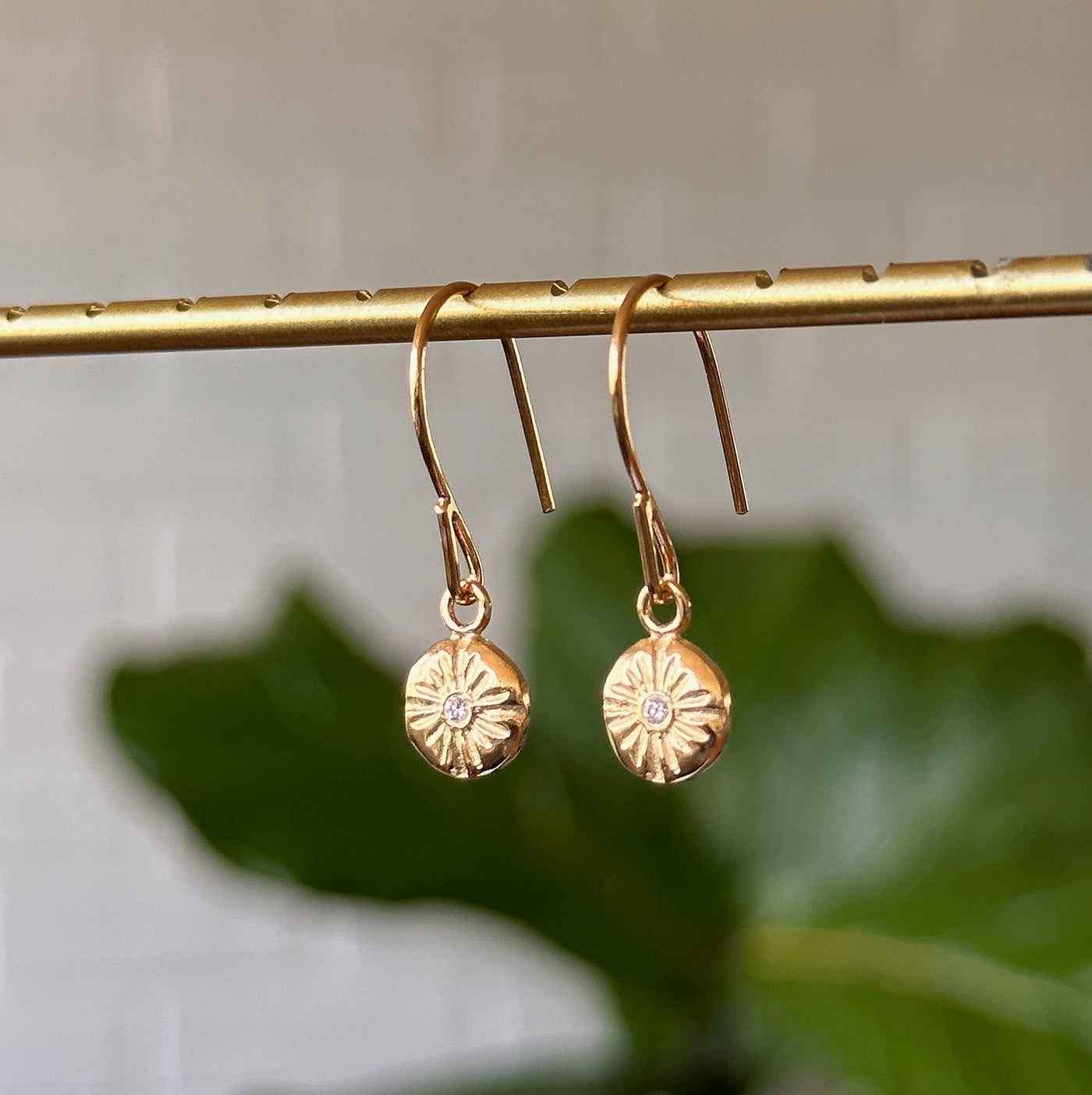 Small Lucia Dangle Vermeil Earrings hanging in front of a white wall, side angle