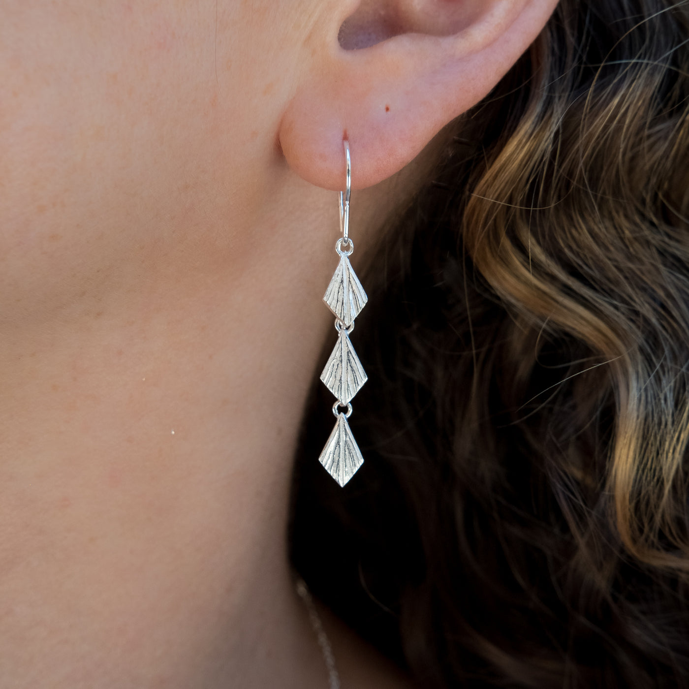 Flame Cascade Silver Dangle Earrings on an ear | Corey Egan