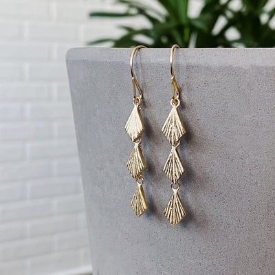 Three overlapping cascading tiers of fan-shaped flame dangles in gold vermeil hanging from an earwire side view