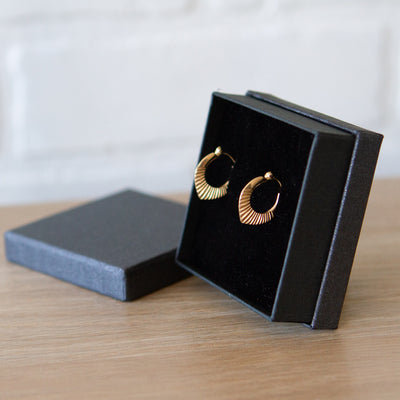 14k yellow gold hinged hoop earrings with carved sunburst motif in a gift box