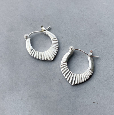 Silver Small Oblong hoops with hinge closure and sunburst bottom by Corey Egan