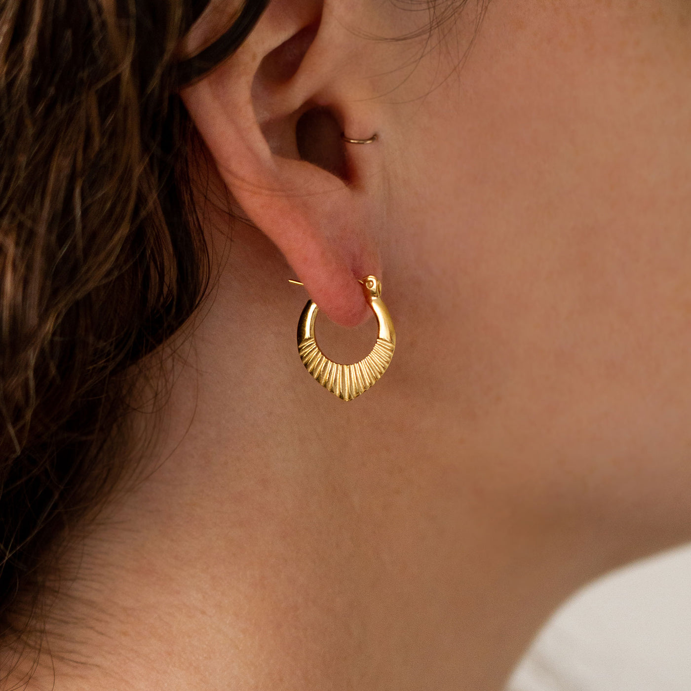 Gold Vermeil Small Oblong hoops with hinge closure and sunburst bottom by Corey Egan on an ear