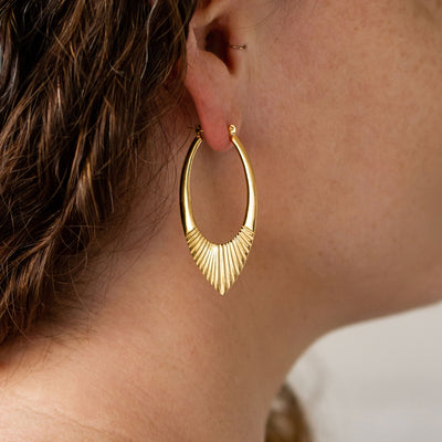 Gold Vermeil Large Oblong hoops with hinge closure and sunburst bottom by Corey Egan on an ear