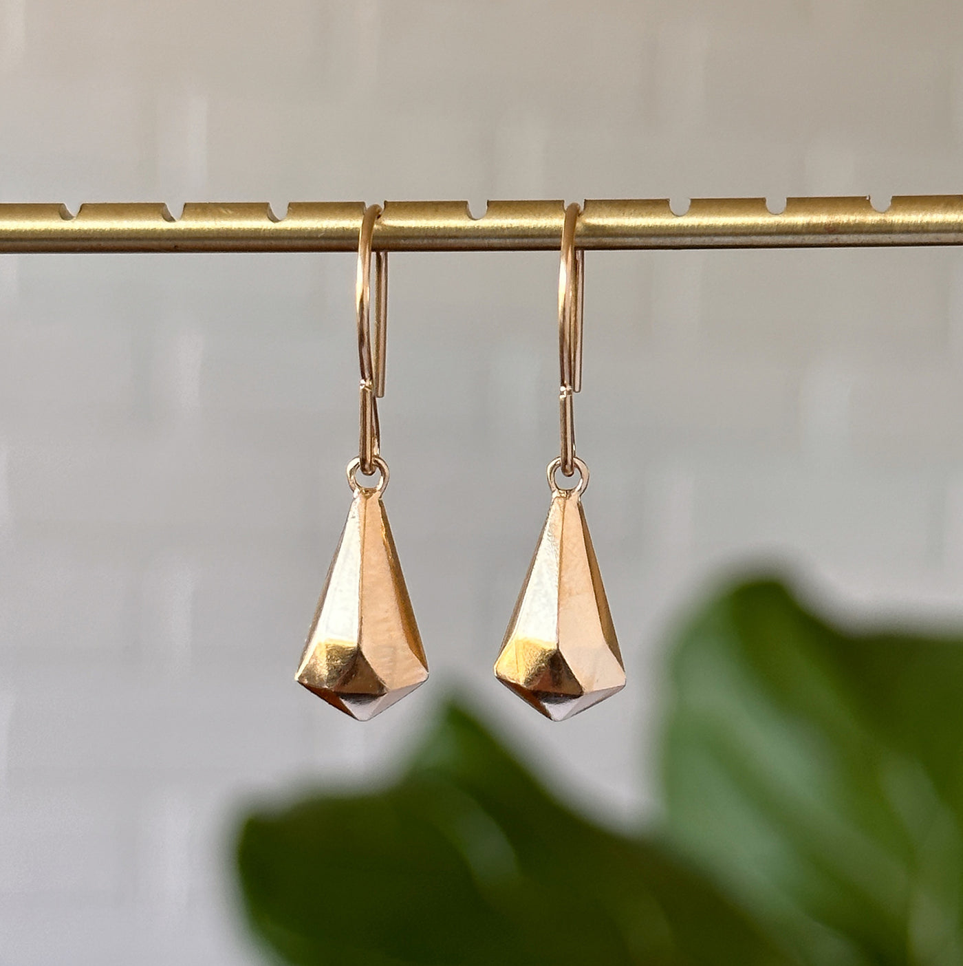 Vermeil Crystal Fragment Earrings hanging in front of a white wall, front angle