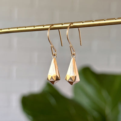 Vermeil Crystal Fragment Earrings hanging in front of a white wall, side angle