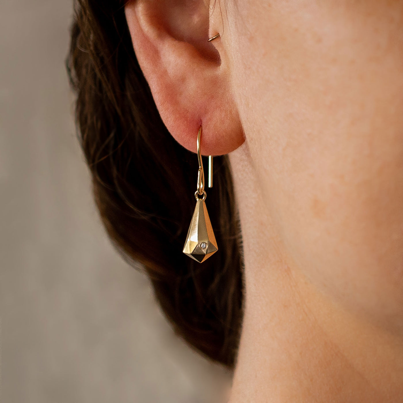 Gold and Diamond Faceted Drop Dangle Earrings on an ear