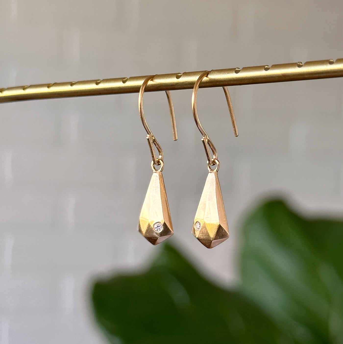 Vermeil and Diamond Crystal Fragment Earrings hanging in front of a white wall, side angle