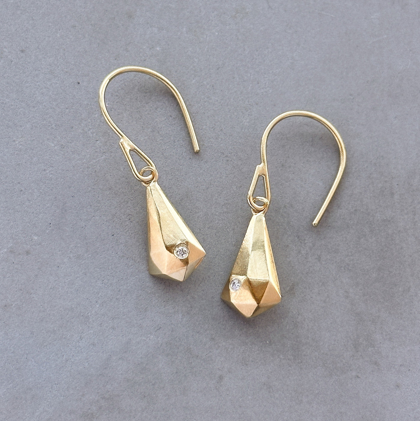 Vermeil and Diamond Crystal Fragment Earrings sitting on a concrete table