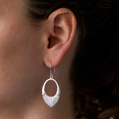 Silver Medium open petal shape earrings with textured bottoms on an ear