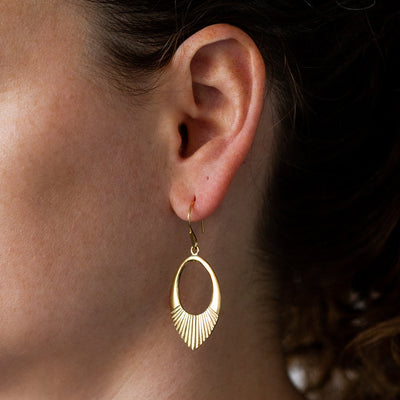 Gold vermeil medium open petal shape earrings with textured bottoms on an ear